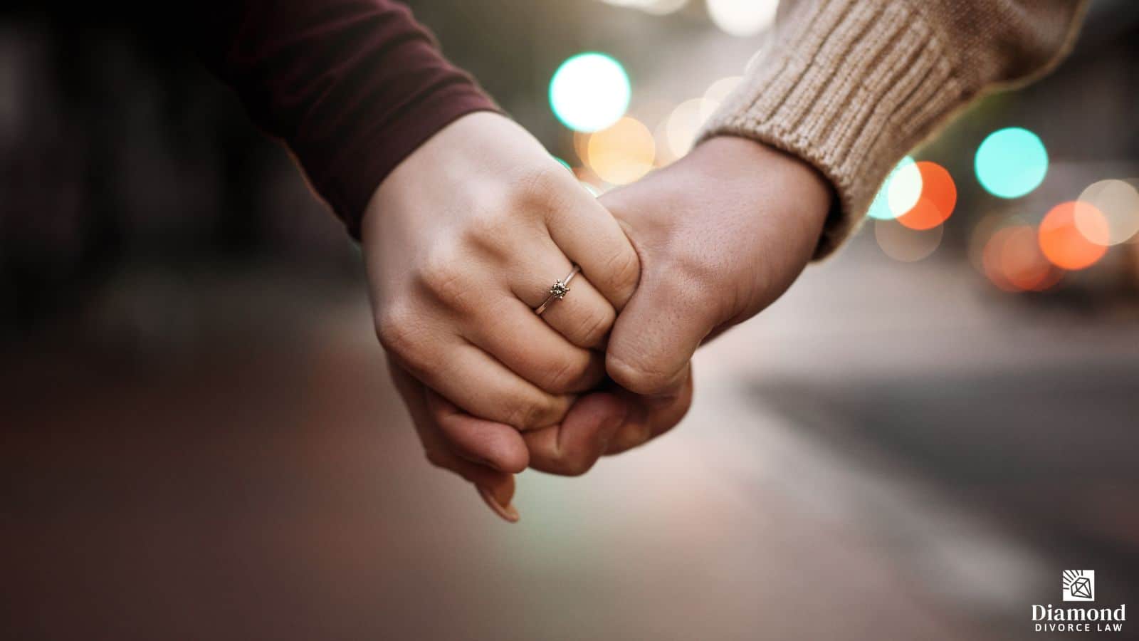 A man and a woman holding hands, she has a wedding ring on.