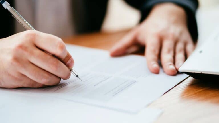 A person filling out paperwork to transfer property into their trust.